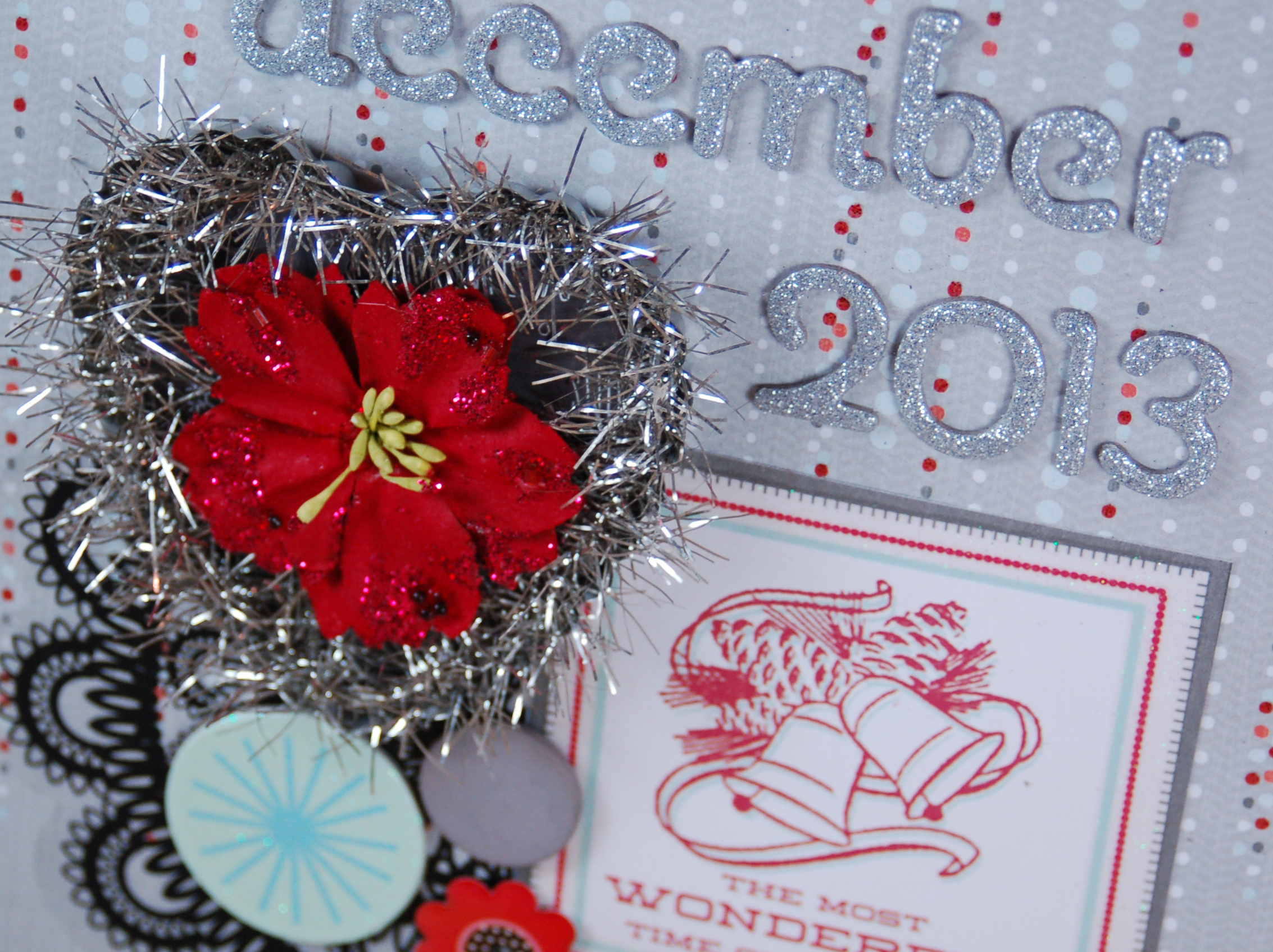 close up of chipboard album covered with silver paper, silver chipboard letter stickers that say December 2013, and an assortment of coordinated and sparkling embellishments